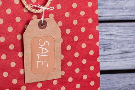 Shopping bag and cardboard price tag. Red paper shopping bag and brown label with inscription sale...