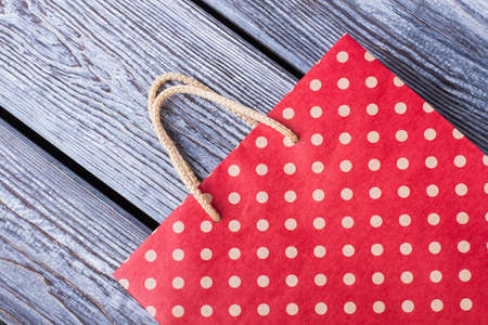 Red shopping bag on wooden boards. Red polka dots paper gift bag on gray wooden background.