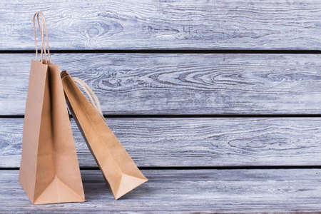 Brown kraft paper bags for gifts. Recycle paper shopping bags on wooden background with text space.の写真素材