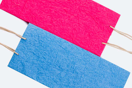 Colored paper gift bags. Close up pink and blue paper shopping bags with rope handles.