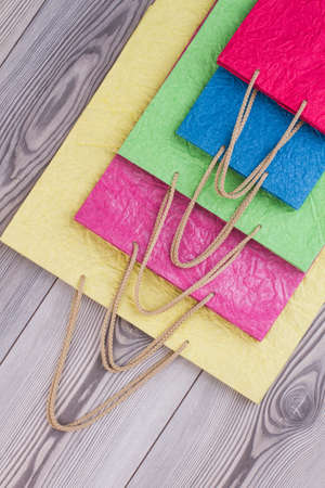 Colorful paper shopping bags, top view. Collection of multicolored gift bags on wooden background. Marketing, commerce and business concept.の写真素材