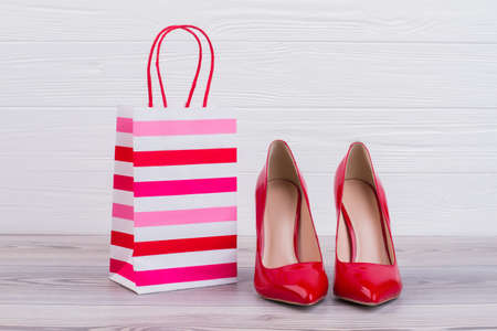 Red stilettos and paper gift bag. Luxury female high heels and paper shopping bag, horizontal image. Way to make woman happy.の写真素材