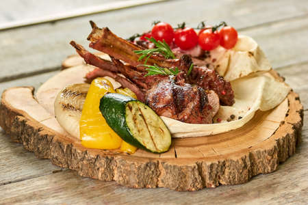 Lamb shrank with side dish on wooden plate. Lamb leg with garnish on wooden plate.の写真素材