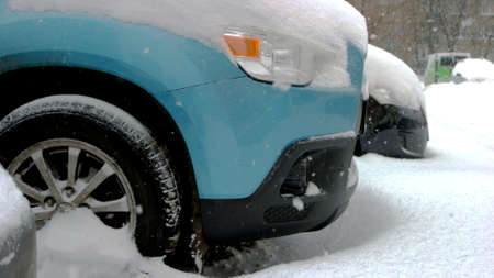 Car wheels stuck in snow drift. Wheel of blue passenger car is stuck in snow. Adverse weather...