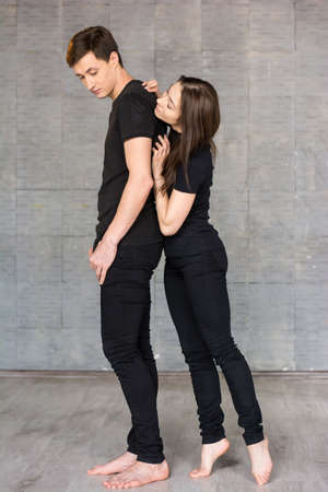 Couple of dancers on studio background. Modern style young woman touching back of her dance partner and looking at him on studio background.の写真素材