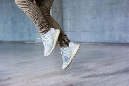 Break dance guy is jumping. Freestyle dancer in movement on grey background, cropped image.の写真素材