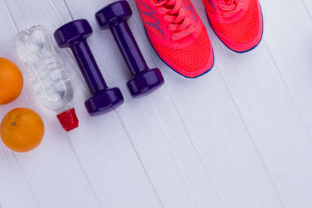 Fitness and weight loss concept. Running shoes, dumbbells, bottle of water, fresh oranges and copy space. Healthy eating, sport and dieting.の写真素材