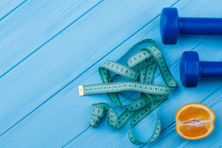 Sport and healthy lifestyle concept. Dumbbells, measuring tape, orange fruit and copy space. Slim body and weight loss concept.の写真素材
