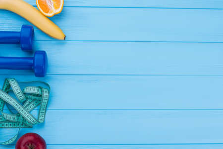 Dumbbells, fresh fruits and measuring tape. Sport, fitness and diet concept. Culture of healthy life.の写真素材