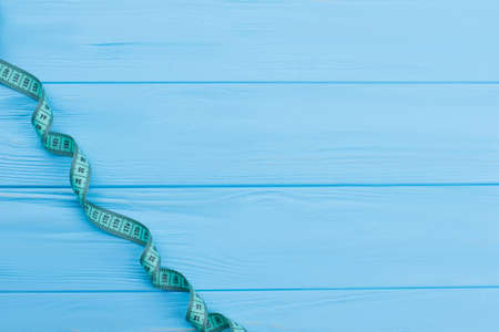 Measuring tape on wooden background with copy space. Tape measure on blue surface with text space. Weight loss control.の写真素材