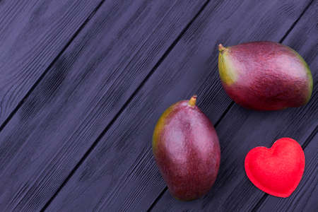 Mango, felt heart and copy space. Whole organic mango fruits and felt handmade heart with text...