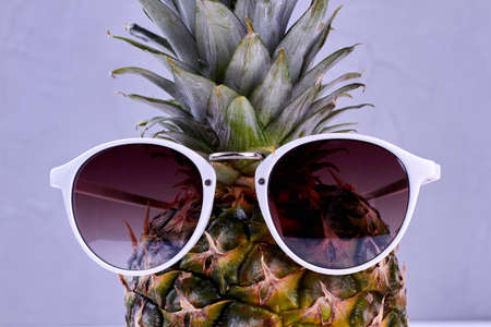 Sunglasses on pineapple. Sunglasses on fresh juicy ananas close up. Summer rest concept.