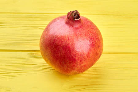 Whole pomegranate on colorful wooden background. Fresh organic pomegranate on yellow wood. Delicious...