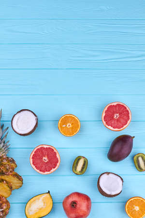 Vibrant tropical fruits and copy space. Variety of fresh exotic fruits on colorful wooden background...