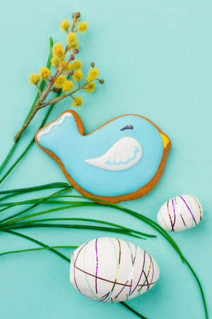 Easter eggs and bird biscuit on grass. Easter eggs, pussy willow and bird shaped cookie close up....