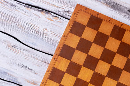 Chess board on wooden background. Empty chess board with copy space, cropped image.
