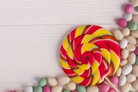 Colored candies on wooden background. Flat lay composition with different candies and space for text on white wooden table.の写真素材