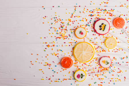 Creative composition with candies, copy space. Delicious fruit shaped lollipops and candies on white wooden background.の写真素材