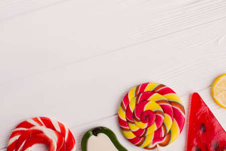 Assorted lollipops on white wood. Various candy lollipops on wooden background with copy space. Greeting card with sweets decor.の写真素材