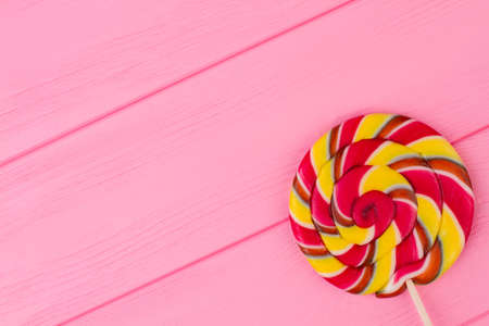 Colorful spiral lollipop candy on stick. Appetizing swirl candy on color background with copy space. Happy Birthday card for kid.の写真素材