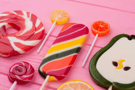 Assorted lollipops on color background. Colorful candies on pink wood. Yummy treats for kids.の写真素材