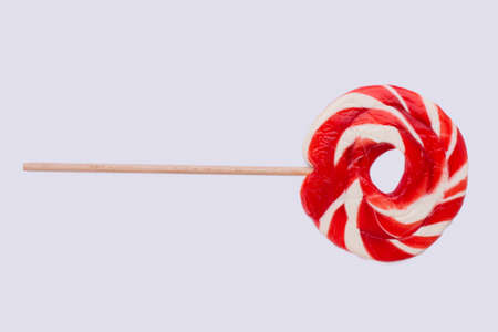 Red large lollipop isolated on white background. Red and white lollipop in the shape of a circle, horizontal image.の写真素材