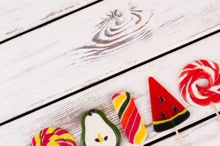 Delicious lollipops on wooden background. Various candies on sticks with copy space. Junk food...