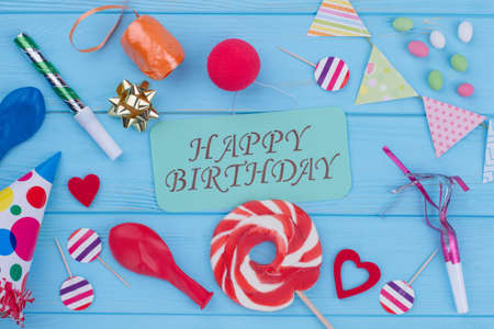 Birthday accessories on wooden background. Flat lay composition with party items and text Happy Birthday on wooden table.の写真素材