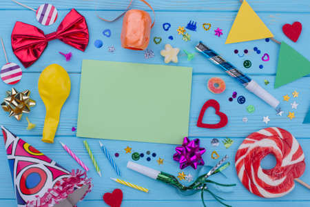 Birthday accessories on blue wood. Flat lay Birthday party supplies and blank paper card. Greeting...