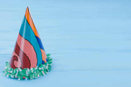Decorative Birthday cap with copy space. Cardboard paper hat on blue wooden background with copy...