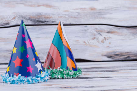 Two Birthday hats on wooden background. Paper cone hats for party celebration on wood background with copy space for greeting.の写真素材