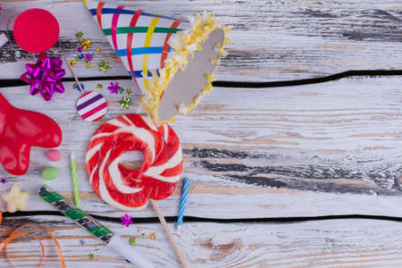 Birthday party items on wooden background. Birthday paper cap, blowers, balloons, candles and lollipop. Holiday greeting background.の写真素材