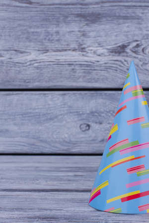 Beautiful party hat with copy space. Blue Birthday carton party cone hat on rustic wooden background...