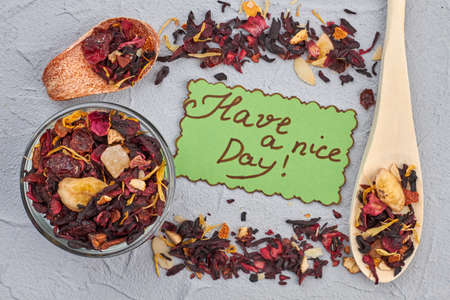 Flat lay composition from hibiscus fruit tea. Spoon, bowl with hibiscus dry tea and paper card with...