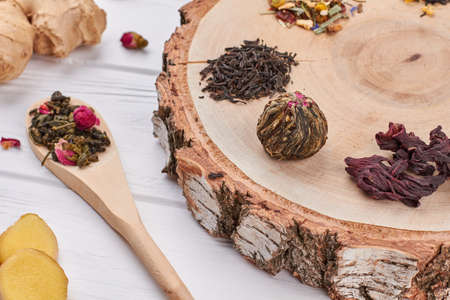 Tea setting close up. Wood disk with different types of dry tea and wooden spoon with dried tea.