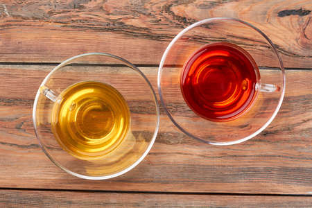 Two cups with hot tea, top view. Glass cups with green and black tea on brown wooden boards. Natural drink for your health.の写真素材