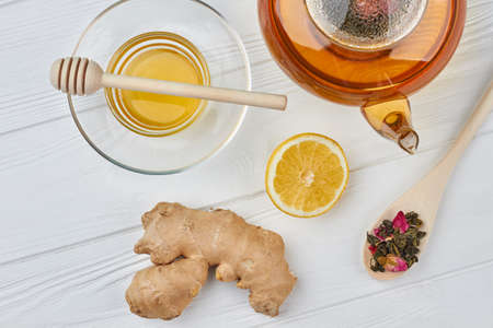 Teapot, honey, ginger and lemon. Tea composition on wooden background. Natural remedy for cold.