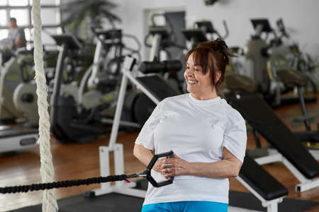 Older woman exercises in modern gym. Happy smiling old woman grandma doing sport workout. Active...