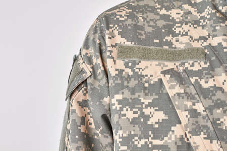 Shoulder of soldier uniform. Extreme close up, white isolated background.