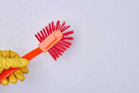 Hand holding toilet brush. Hand in yellow rubber glove holding brush with plastic handle. Space for...