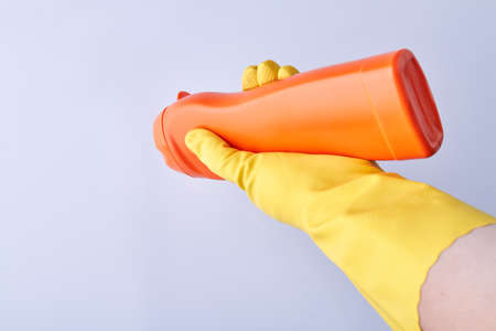 Hand in glove holding plastic bottle with detergent. Household chemicals. Cleaning product.の写真素材
