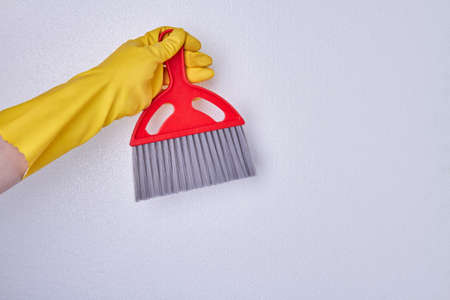 Hand with glove holding cleaning broom. Person in rubber glove holding red cleaning brush. Space for text.の写真素材