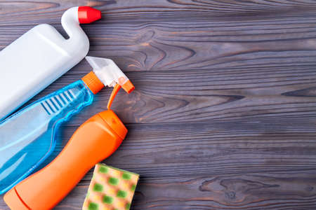 House cleaning supplies on wooden background. Set of plastic bottles with cleaning liquid and kitchen sponge. Space for text.の写真素材