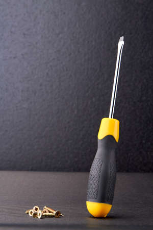 Screwdriver and screws on dark background. Tools for construction or repair.の写真素材