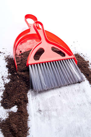 Mud spilled from potted plant on floor at home. Dustpan, soil and broom on the floor. Household chores concept.の写真素材