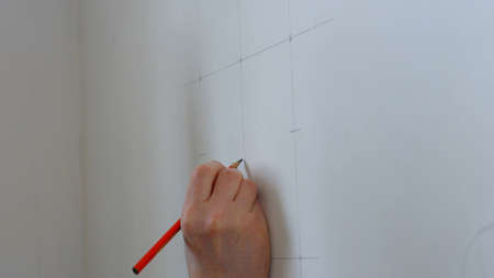 Hand make wall marking with pencil. Construction worker using pencil to mark a wall close up.の写真素材