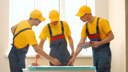 Construction workers discussing new project plan. Three builders are discussing a new project of building a house. Concept of construction.の写真素材