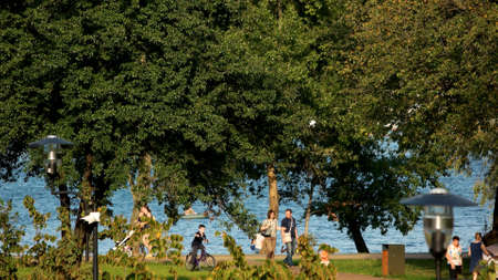 17.09.2017 - Kyiv, Ukraine. Lake and trees in city park. People walking outdoor on sunny day. Park in summer.のeditorial素材