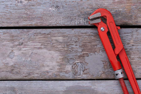 Adjustable red pipe wrench on wooden background. Adjustable wrenches on wooden boards with copy space.の写真素材