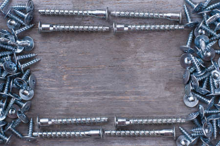 Frame from screw nails on wooden background. A lot of silver screws and copy space. Repair concept.